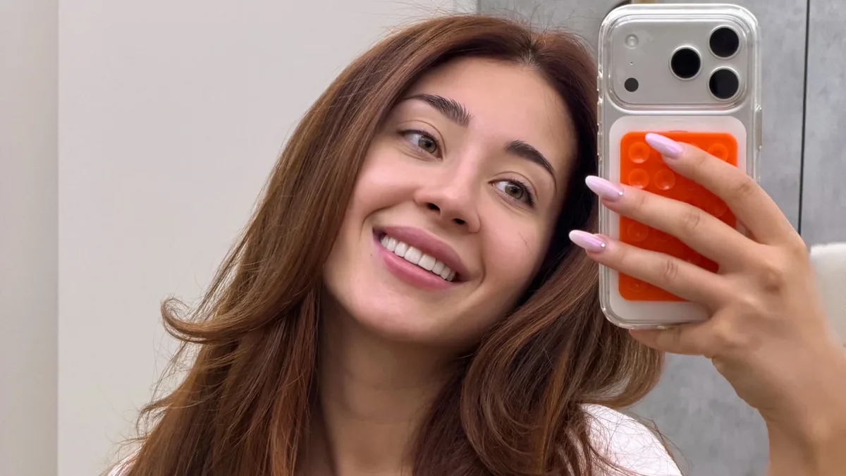 Nicole Cherry zâmbește într-un selfie în oglindă, cu telefonul ridicat lângă față.