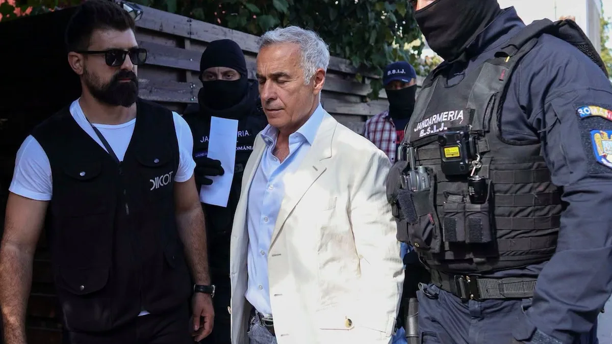 Călin Georgescu, în sacou deschis, alături de un bărbat cu vestă DIICOT și de jandarmi mascați.