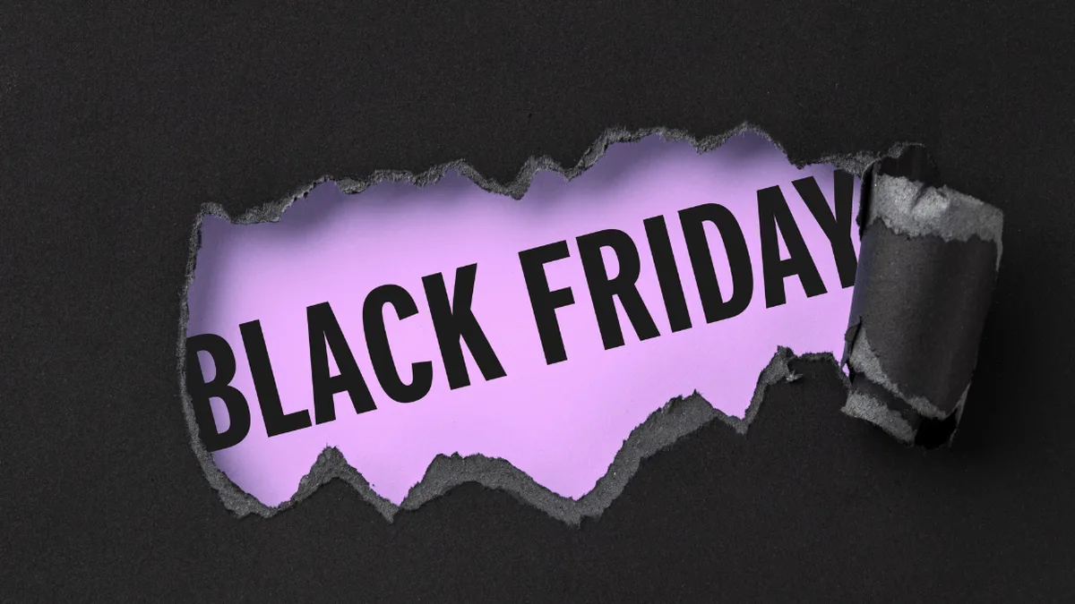 Textul „BLACK FRIDAY” pe fundal mov, vizibil printr-o ruptură în hârtia neagră.