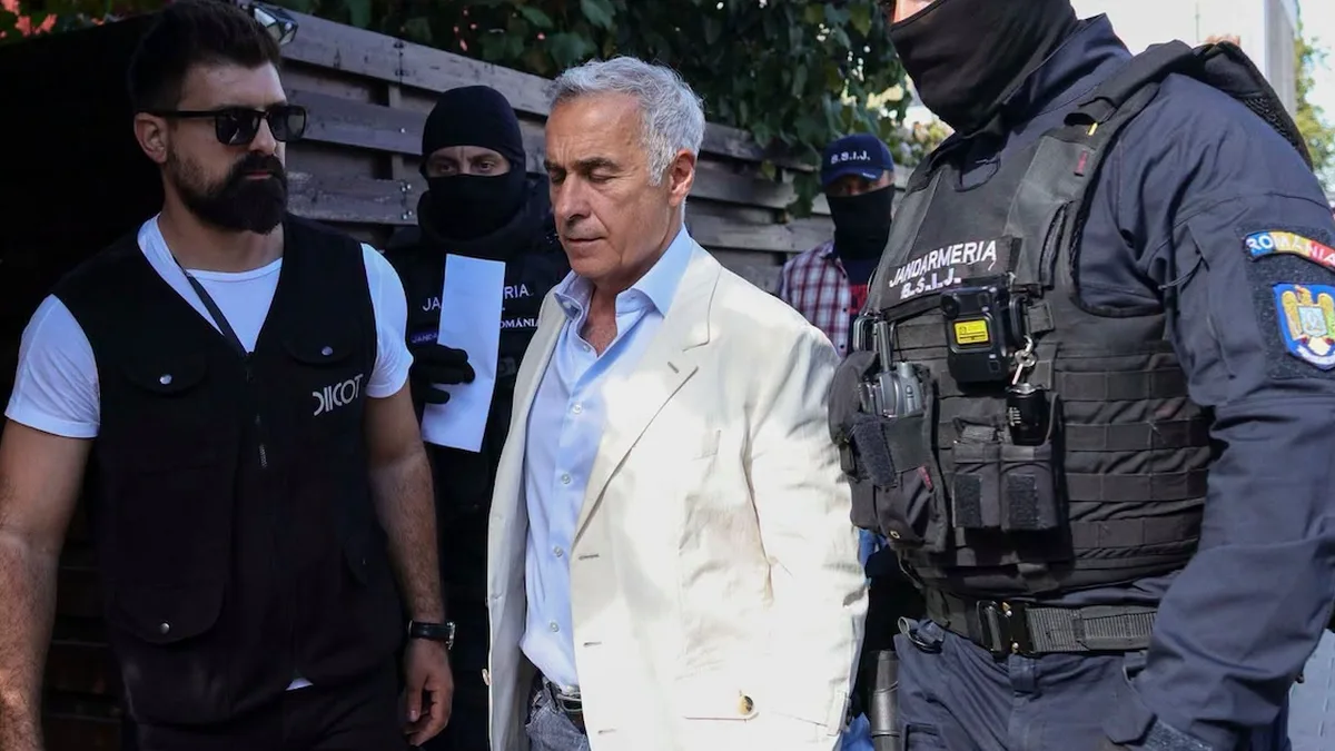 Călin Georgescu, în sacou deschis, între un bărbat cu vestă DIICOT și jandarmi cu echipament tactic.