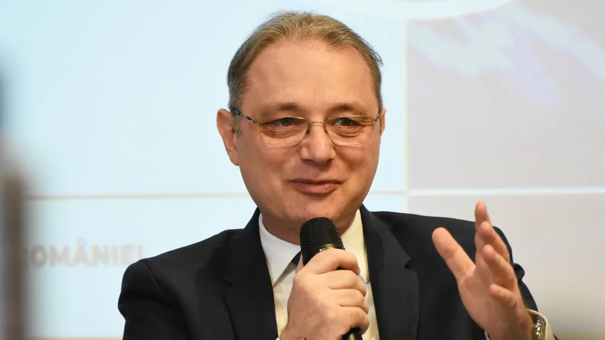 Luca Niculescu vorbește la un microfon ținut în mână și gesticulează.