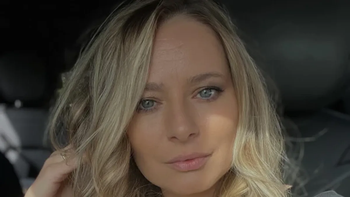 Laura Cosoi, cu părul ondulat și tricou gri, privește spre cameră din interiorul unei mașini.