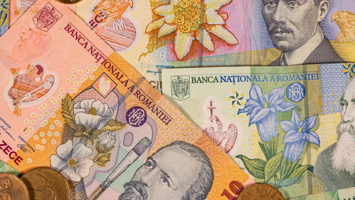 Bancnote românești suprapuse și monede, cu o bancnotă de 10 lei în prim-plan.