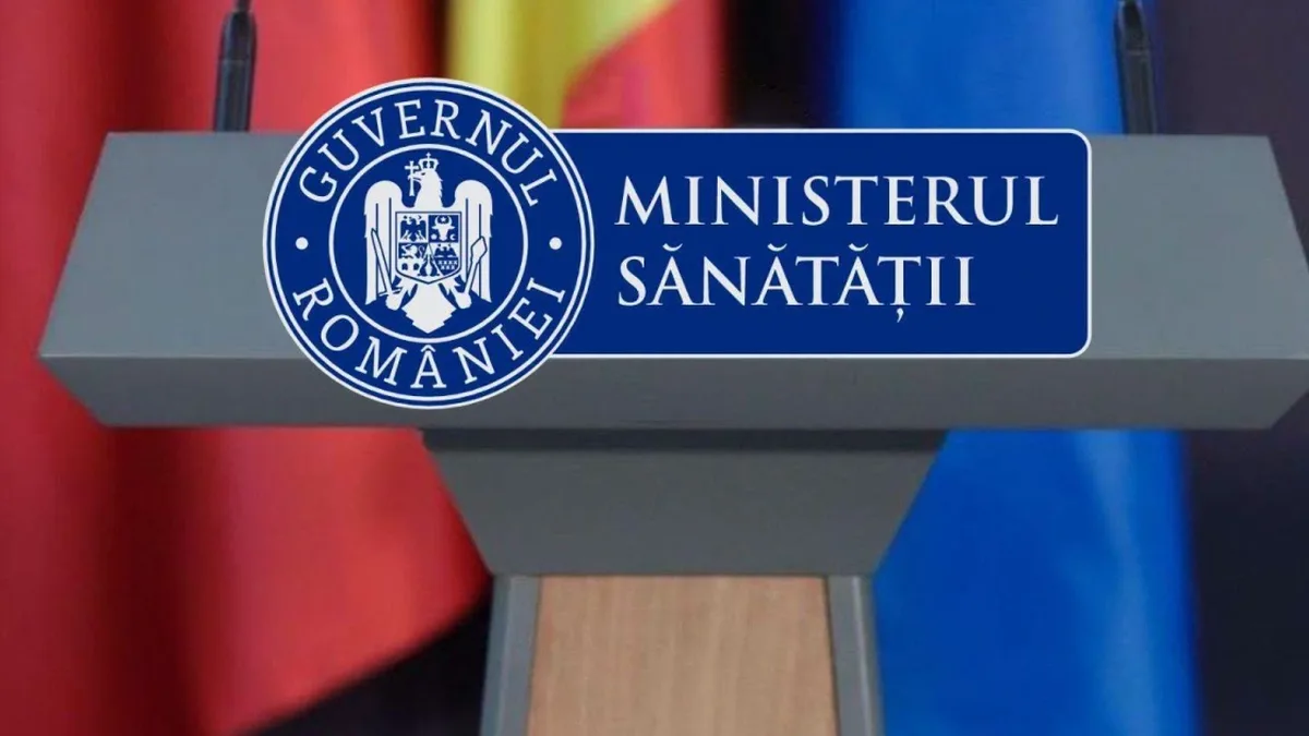 Pupitru cu însemnele Guvernului României și inscripția „Ministerul Sănătății”, două microfoane și drapele în fundal.