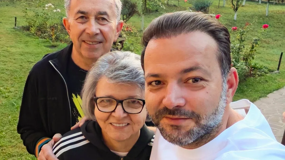 Mihai Morar, în prim-plan, alături de o femeie cu ochelari și un bărbat, într-o grădină.